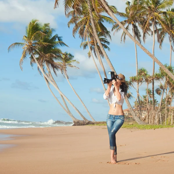 Donna di moda sulla spiaggia tropicale con macchina fotografica — Foto Stock