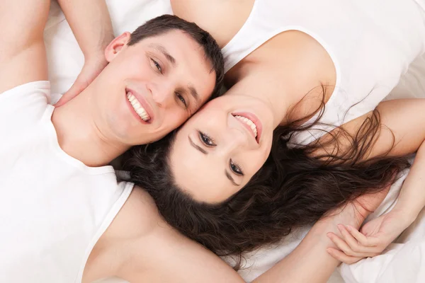 Młoda szczęśliwa para leży w łóżku biały — Zdjęcie stockowe