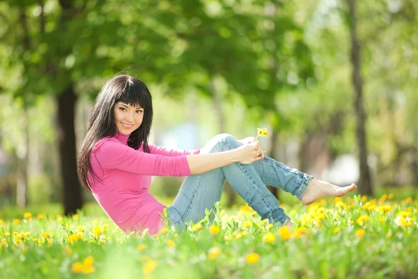 Femme mignonne dans le parc avec des pissenlits — Photo