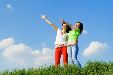 Two young women on a green meadow clipart