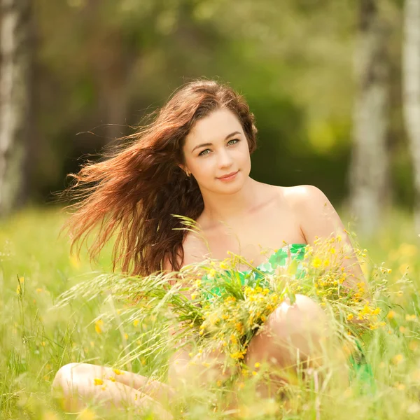 Fiatal vöröshajú asszony a parkban, virágok — Stock Fotó