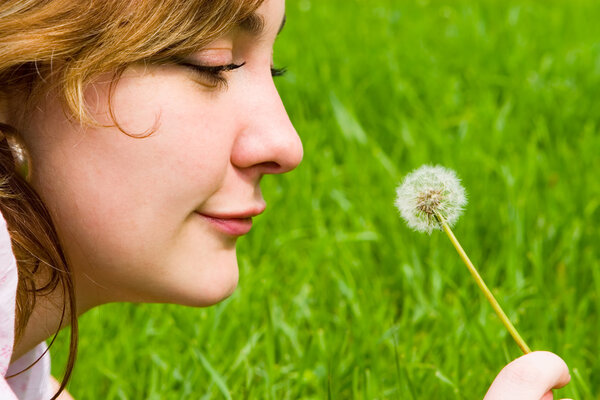 Happy girl blowing on the dandelion