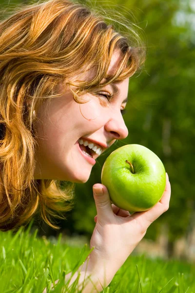 Pretty woman eating green apple on the summer glade — Stock Photo, Image