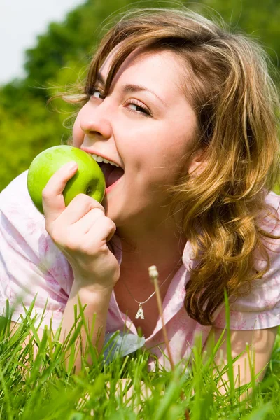 Mooie vrouw groene appel eten op de zomer-glade — Stockfoto