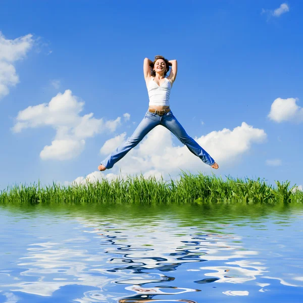 Happy young woman jumping in green grass — Stock Photo, Image
