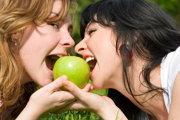 Hübsche Frauen essen grüne Äpfel auf der Sommerwiese — Stockfoto