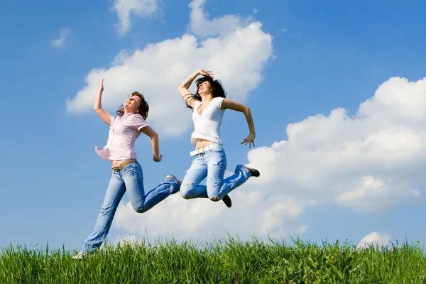 Deux femmes heureuses sautant sur l'herbe verte — Photo