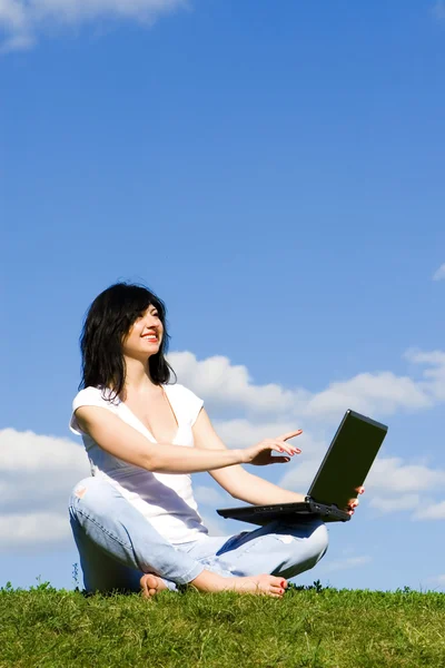 Όμορφη γυναίκα με φορητό υπολογιστή στο πράσινο γρασίδι — Φωτογραφία Αρχείου