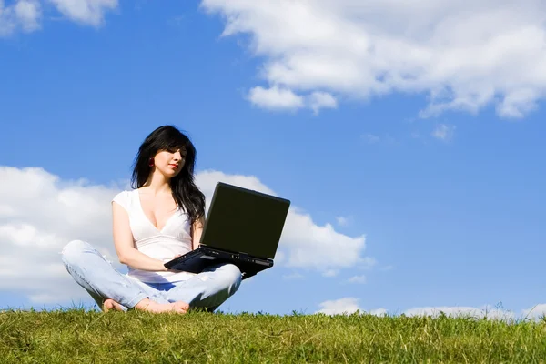 Mujer bonita con el ordenador portátil en la hierba verde — Foto de Stock