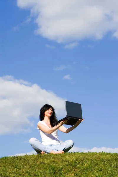 Mujer bonita con el ordenador portátil en la hierba verde — Foto de Stock