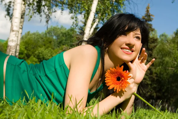 Mooie vrouw rust in het park met bloem — Stockfoto