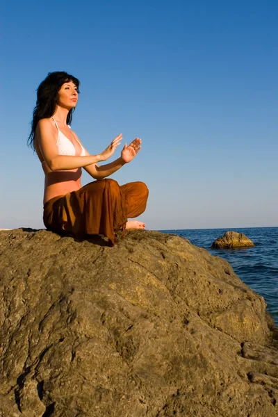 Junge Frau meditiert am Strand — Stockfoto