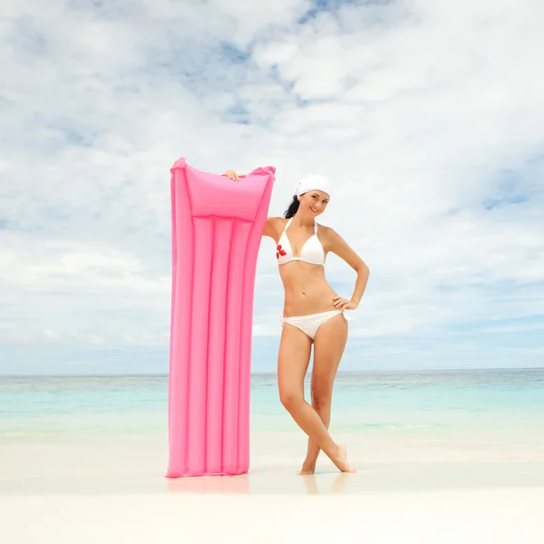 Счастливая женщина с надувным матрасом на пляже — стоковое фото