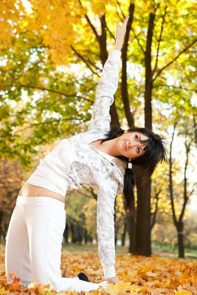做瑜伽练习在秋天公园里的漂亮女人 — 图库照片