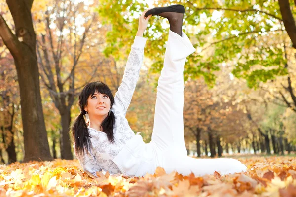 Pretty woman doing yoga exercises in the autumn park — Stock Photo, Image