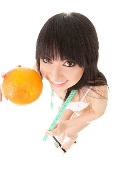 Mujer divertida con naranja y cinta métrica en las escamas de vidrio — Foto de Stock