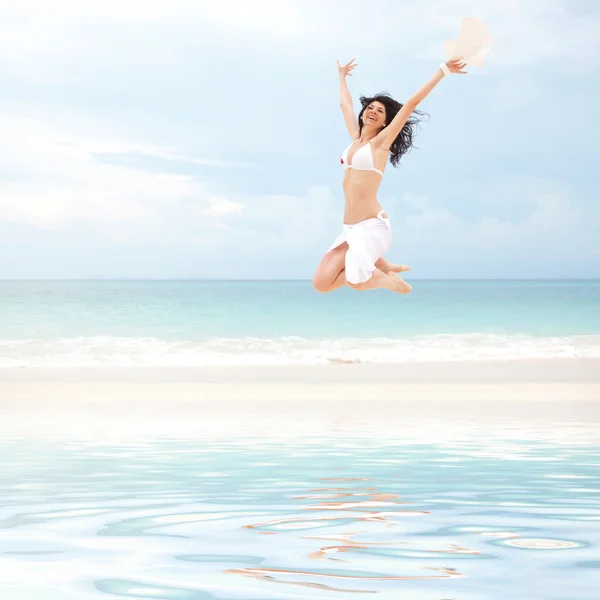 Glückliche junge Frau springt am Strand — Stockfoto