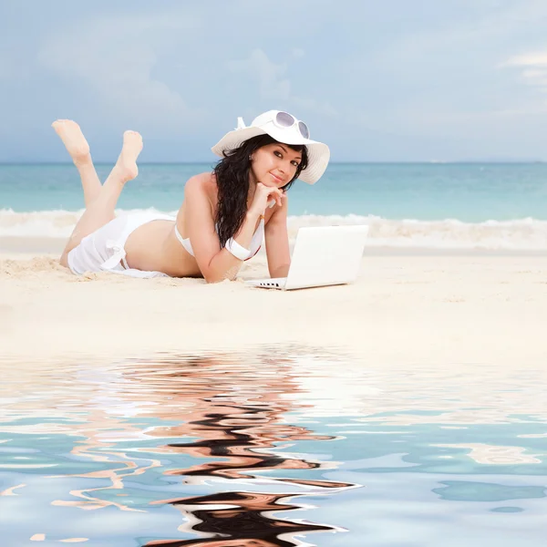 Carino donna con computer portatile bianco sulla spiaggia estiva — Foto Stock