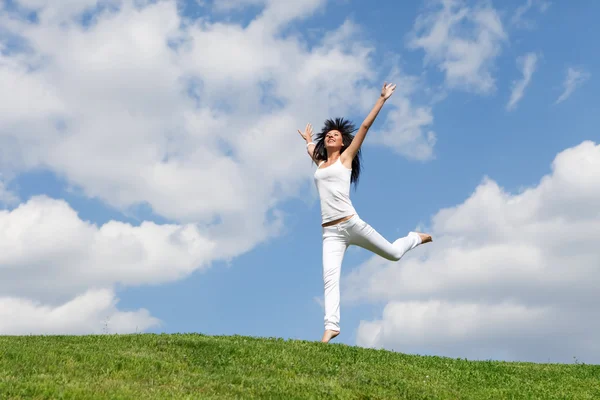 Mooie jonge vrouw springen op groen gras — Stockfoto