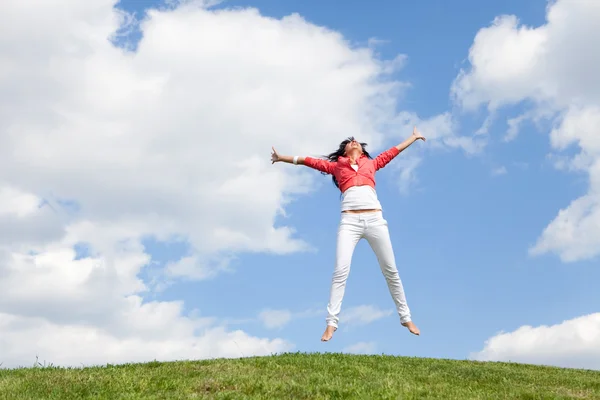 Hübsche junge Frau springt auf grünem Gras — Stockfoto
