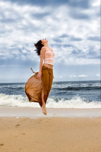 Mujer joven está saltando en la playa — Foto de Stock
