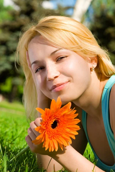 Hübsche Frau ruht sich im Park mit Blumen aus — Stockfoto