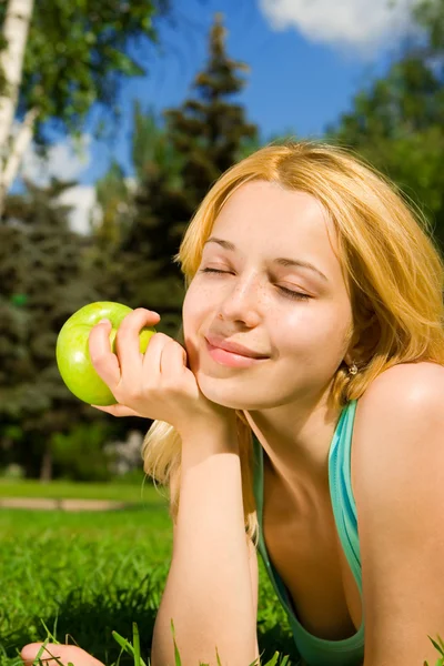 Pretty woman eating green apple on the summer glade — Stock Photo, Image