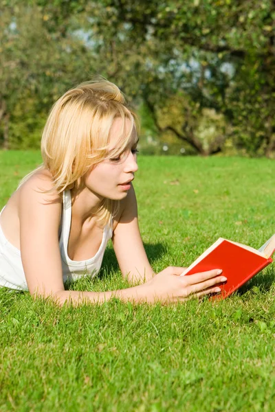 Junge Blondine liest Buch im Park — Stockfoto