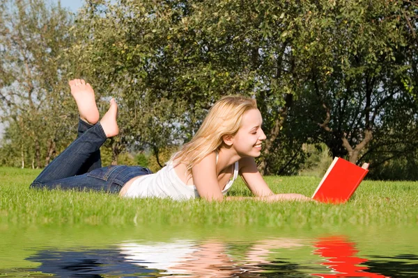 Giovane bionda legge libro nel parco — Foto Stock