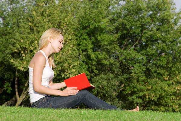 Unga blonda läser bok i parken — Stockfoto