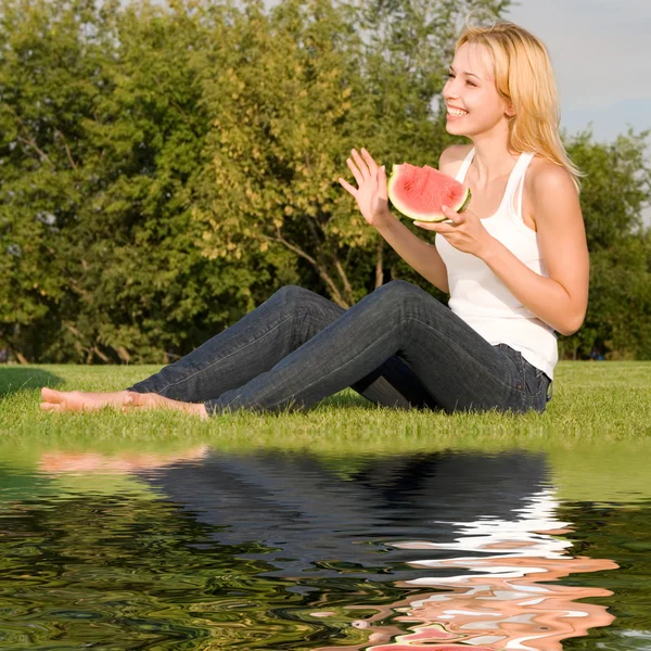 Fiatal szőke eszik görögdinnye a parkban — Stock Fotó