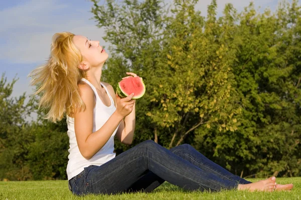 Fiatal szőke eszik görögdinnye a parkban — Stock Fotó