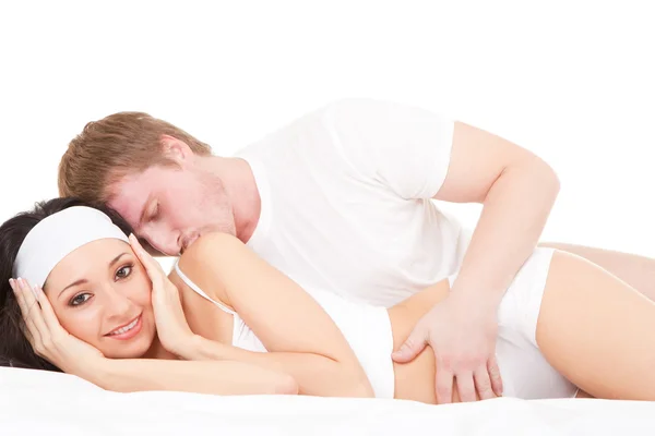 Mladý šťastný pár ležící na bílé posteli — Stock fotografie
