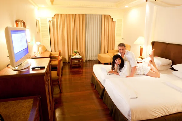Giovane coppia con computer portatile bianco sdraiato sul letto in camera d'albergo — Foto Stock