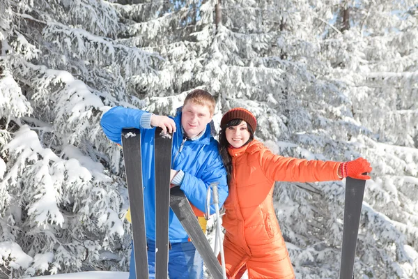Pareja feliz con esquí en el paisaje invernal — Foto de Stock