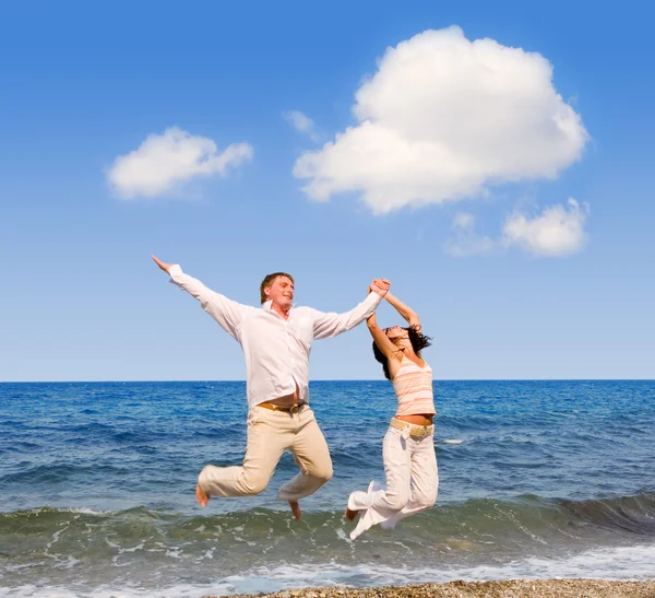 Pasangan muda yang bahagia melompat di pantai — Stok Foto