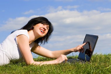 Yeşil çimenlerin üzerinde laptop ile komik kadın
