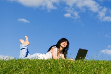 Yeşil çimenlerin üzerinde laptop ile güzel kadın