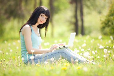 sevimli kadın karahindiba parkta beyaz dizüstü bilgisayar ile