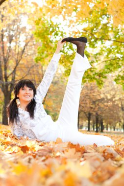 güzel bir kadın yoga egzersizleri sonbahar Park yapıyor