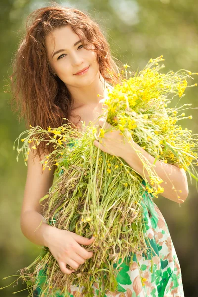Jonge redhead vrouw in het park met bloemen — Stockfoto