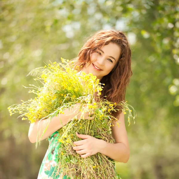 Молода руда жінка в парку з квітами — стокове фото