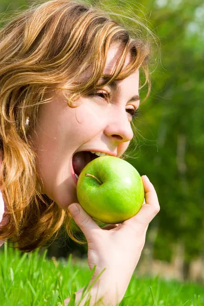Jolie femme mangeant de la pomme verte sur la clairière d'été — Photo