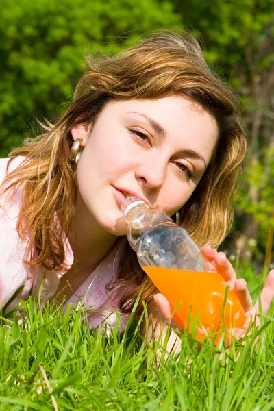Красивая женщина пьет сок на летней поляне — стоковое фото