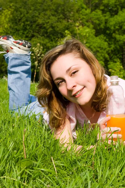 Pretty woman drinking juice on the summer glade — Stock Photo, Image