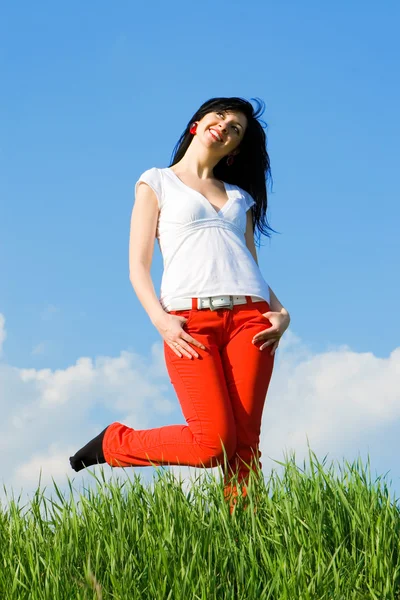 Mooie vrouw op groene gras en hemel achtergrond — Stockfoto