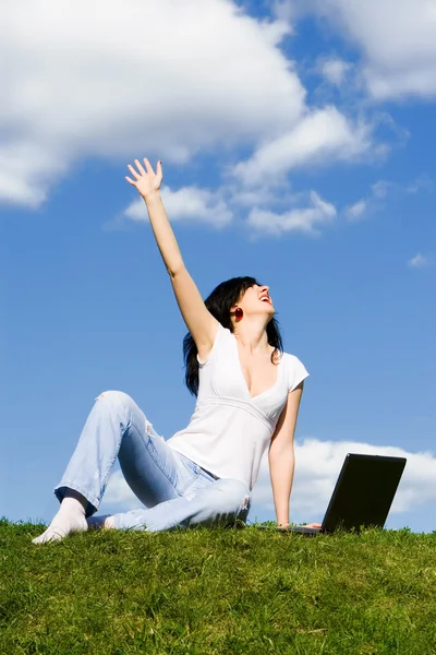 stock image Expressive woman with laptop on the green grass