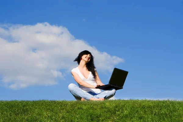 Гарна жінка з ноутбуком на зеленій траві — стокове фото