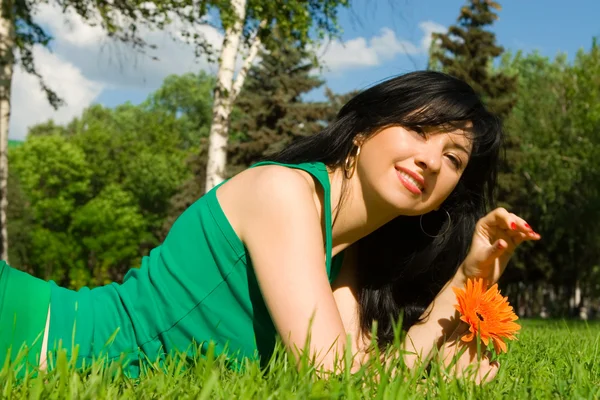 Ładna kobieta odpoczynku w parku z kwiatem — Zdjęcie stockowe