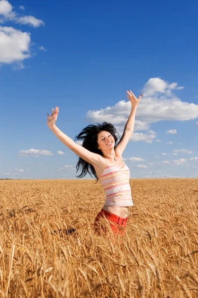 Happy woman jumping in golden wheat — Stock Photo, Image